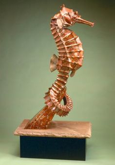 a bronze sea horse sculpture sitting on top of a wooden block