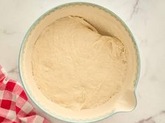 a bowl filled with dough sitting on top of a white and red checkered table cloth