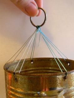 a person is holding a tiny ring in a tin can with string attached to it