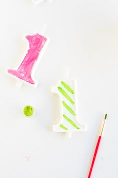 two birthday candles are sitting next to a paintbrush and some other crafting supplies