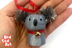 a hand holding a small toy with some hair on it's head and a bell around its neck