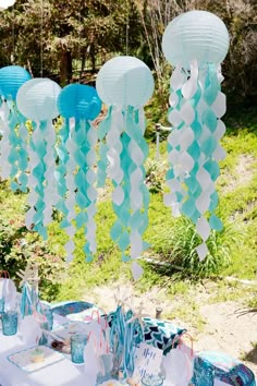 a table topped with lots of blue and white paper lanterns hanging from it's ceiling