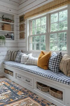 a window seat with several pillows on it in front of a rug and windowsill