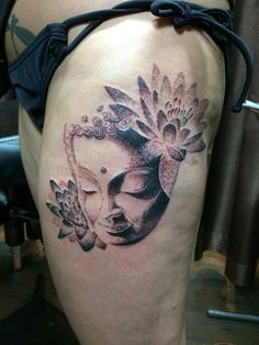 a woman's thigh with an artistic tattoo design on her leg and the face of a buddha