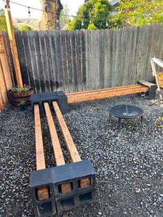 a wooden bench sitting in the middle of a gravel covered yard next to a fence