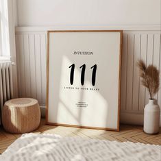 a white framed poster with the number 11 on it next to a small round stool