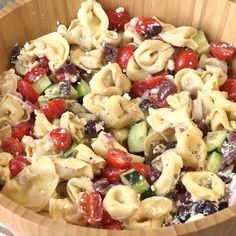 a wooden bowl filled with pasta salad on top of a table