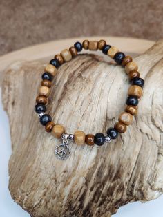 This bracelet is created with all varieties of wooden beads. It has different shades of browns with a peace sign charm hanging from it. It's earthy boho style ties together the beautiful simplicity of nature as well as the calming effects of peace. Both men and women can rock this accessory, as it is very neutral in it appearance! Wooden Beads Jewelry Greatergood, Cheap Bohemian Stretch Bracelet With Wooden Beads, Wooden Beads Jewelry, Bracelets Hippie, Wooden Bead Jewelry, Wooden Bead Bracelet, Wood Beads Jewelry, Wooden Beaded Bracelets, Hippie Accessories