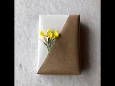 a piece of brown paper with yellow flowers on it sitting on a white counter top