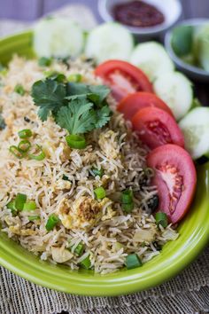 a green bowl filled with rice, tomatoes and cucumbers