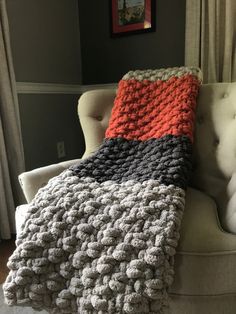 a crocheted blanket sitting on top of a couch next to a white chair