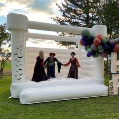 three women standing in front of an inflatable arch with balloons and decorations on it