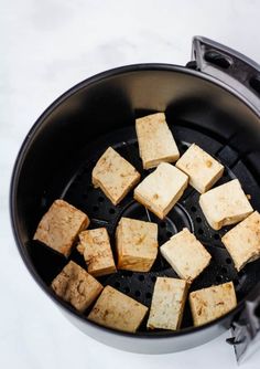 tofu cubes being cooked in a frying pan on a white counter top