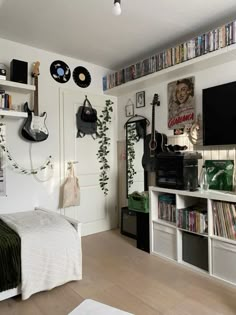 a bedroom with white walls and lots of books on the shelves, guitar headphones hanging from the wall