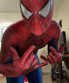 a man in a spiderman costume poses for the camera while holding his hands up