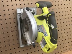 a cordless circular saw is on the wall next to a tool holder and screwdriver