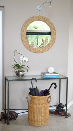 an umbrella is sitting in a basket next to a table with a mirror on it