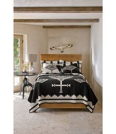 a bed with a black and white comforter in a room next to a table