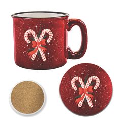 a red coffee mug with candy canes on it next to a white plate and cork coaster