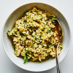 a white bowl filled with food next to a spoon