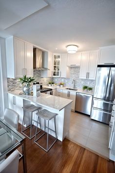 a kitchen with stainless steel appliances and white cabinets, wood flooring and hard wood floors