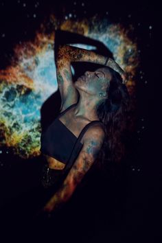 a woman with tattoos on her arm and arms is posing in front of an image