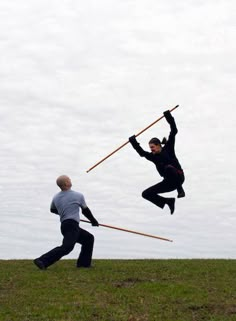 two men are playing with sticks in the grass