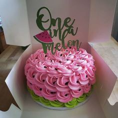 there is a cake in the box with pink icing and green decorations on it