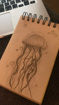 a drawing of a jellyfish on a notebook next to a laptop