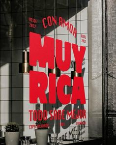 a sign that says muy rica on the side of a building with potted plants