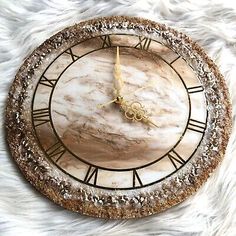 a clock that is sitting on top of a white fur rug with gold numbers and roman numerals