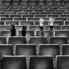 black and white photograph of two people's feet in the middle of an empty auditorium