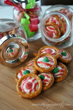 some cookies are on a wooden table with candy canes in the jar behind them