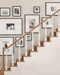 a stair case with pictures on the wall and framed photos above it, along with a wooden handrail