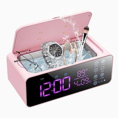 a pink alarm clock with two watches in it and some water on the table next to it