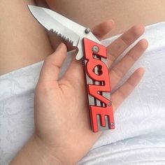 a person holding a knife with the word love spelled out in red on it's blade