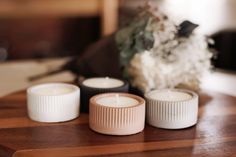 three white candles sitting on top of a wooden table