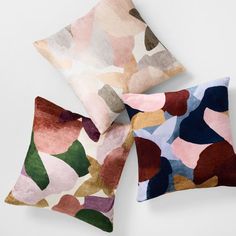 three pillows with different colored shapes on them