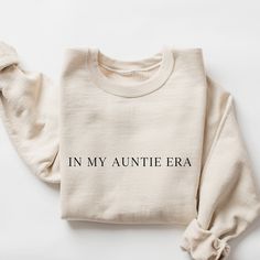 a white sweater with the words in my ant era printed on it, sitting on a white surface