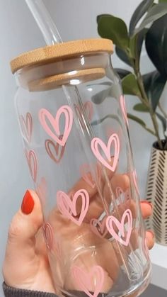 a person holding a jar with hearts painted on the inside and pink writing on the outside