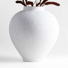 a white vase with some plants in it