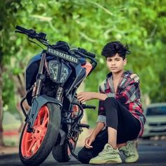 a young man sitting on the ground next to a motorcycle