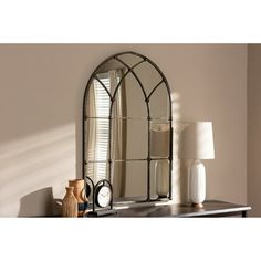 an arched mirror sitting on top of a table next to a lamp and vases