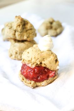 three cookies with strawberry jam and whipped cream on them sitting on a white towel next to each other