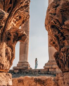 a woman standing in between two stone pillars