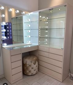 a dressing table with lighted lights on it and a stool in front of the mirror