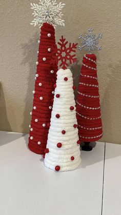 three crocheted christmas trees sitting on top of a white table next to each other