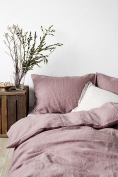 a bed that has some pillows on top of it and a plant in the corner