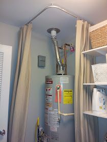 a water heater sitting in the corner of a bathroom next to a shower curtain