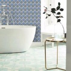 a white bath tub sitting in a bathroom next to a window with blue tiles on it